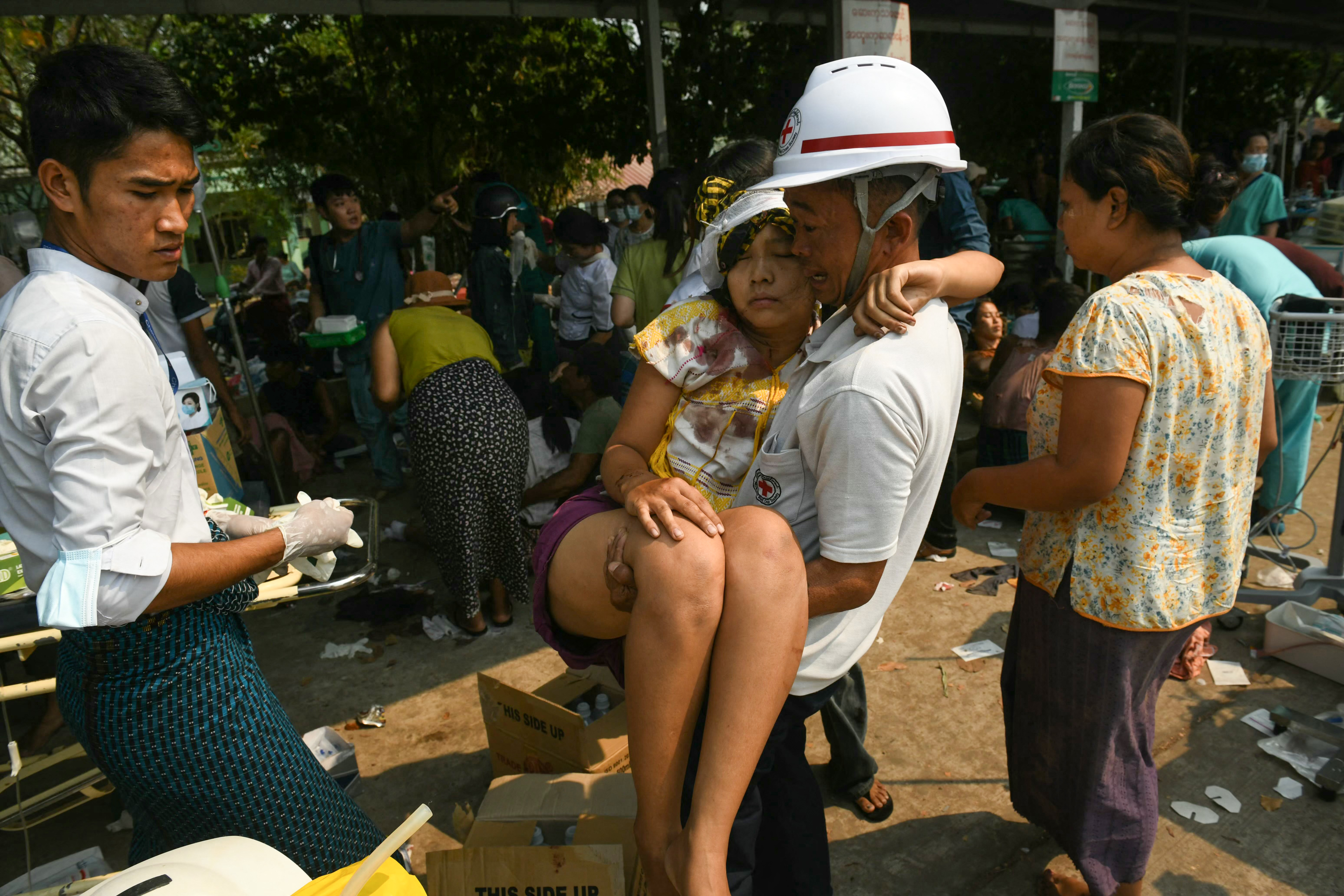 An earthquake survivor is carried as she waits to receive medical attention