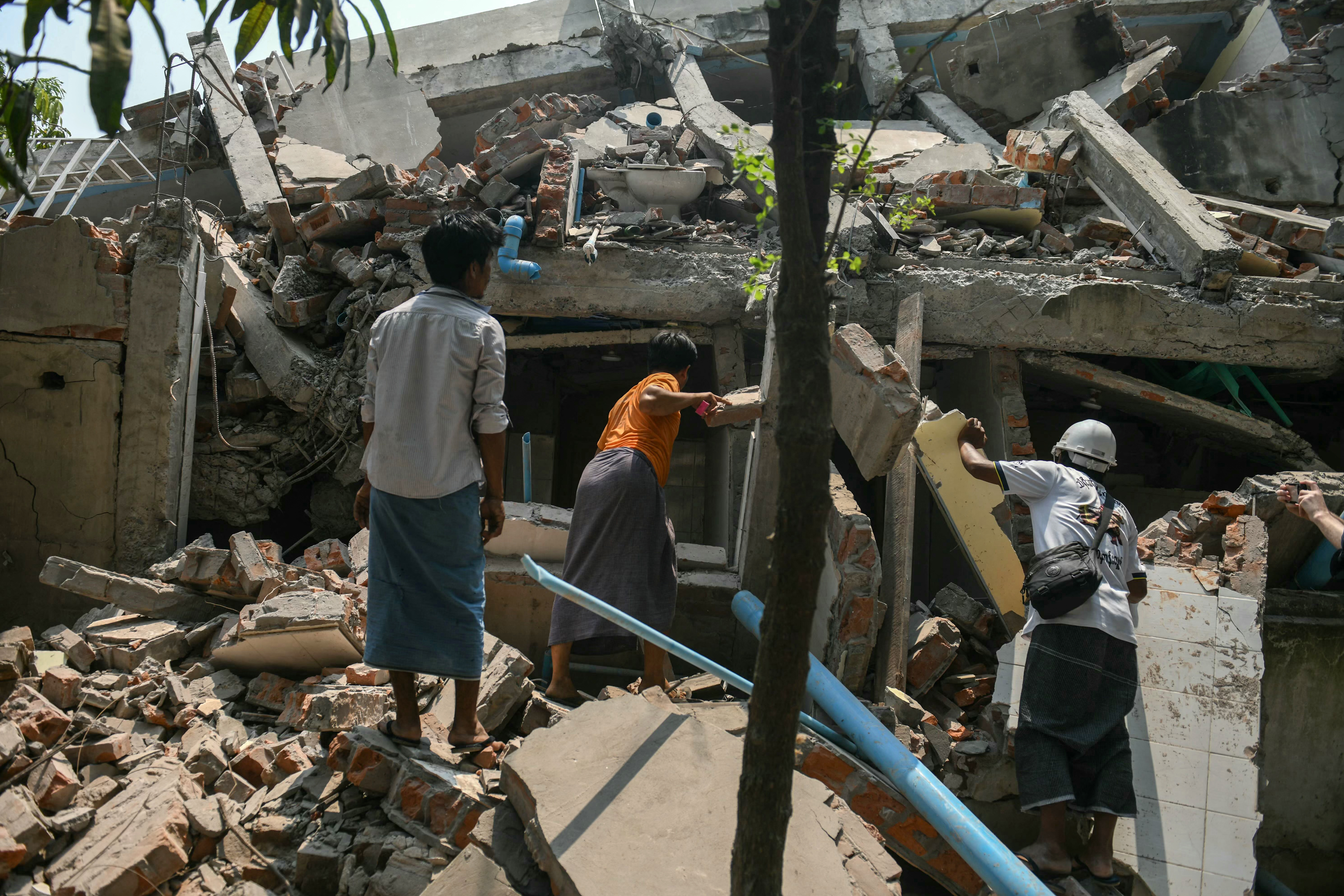 People search through the debris of a destroyed building as they look for survivors in Mandalay