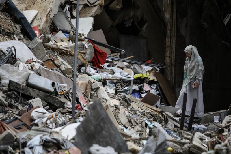 A woman standing amid the debris of a destroyed building.