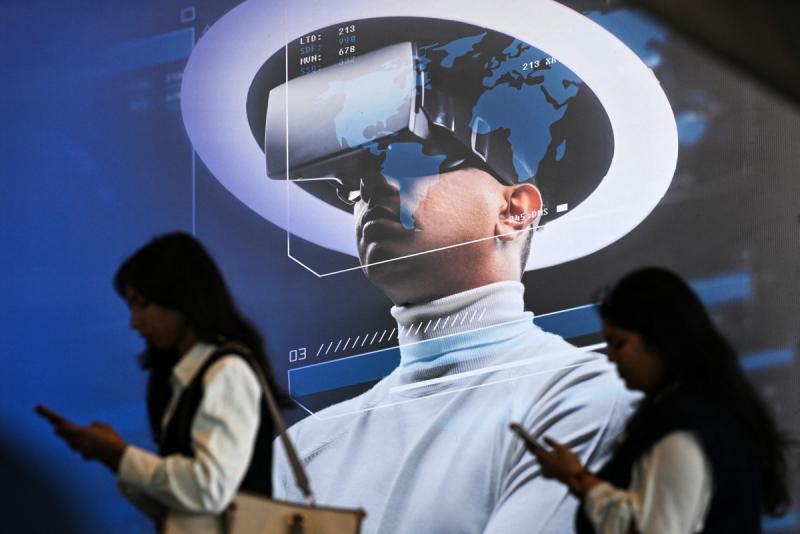 Des visiteurs et un casque de réalité virtuelle affiché lors de l'AI Impact Summit. 