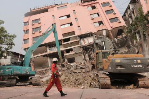 A rescue worker walks past heavy construction equipment being used to clear rubble